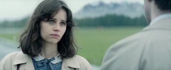 Movie still from “The Theory of Everything” (2014), directed by James Marsh – A young woman standing next to a man in a grassy field; Close Up shot, Over the shoulder angle