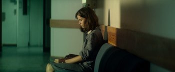 Movie still from “The Theory of Everything” (2014), directed by James Marsh – A woman sitting on a bench looking at her phone; Medium shot, High angle