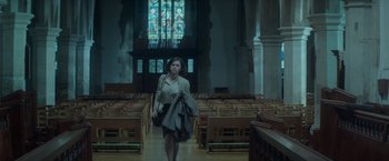 Movie still from “The Theory of Everything” (2014), directed by James Marsh – A woman walking through a church holding a purse; Wide shot, High angle