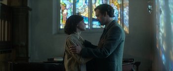 Movie still from “The Theory of Everything” (2014), directed by James Marsh – A man and a woman standing next to each other in front of a stained glass window; Medium shot, Low angle