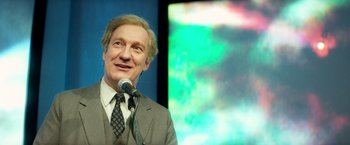 Movie still from “The Theory of Everything” (2014), directed by James Marsh – A man standing in front of a microphone; Medium shot, Over the shoulder angle