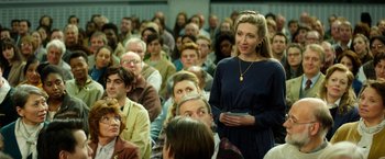 Movie still from “The Theory of Everything” (2014), directed by James Marsh – A woman standing in front of a group of people; Medium shot, Over the shoulder angle