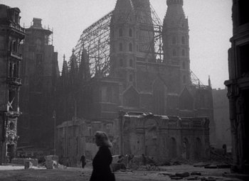 An old photo of a woman walking in front of an old church