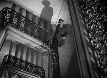 Movie still from “The Third Man” (1949), directed by Carol Reed – A black and white photo of a man standing on a staircase; Wide shot, Low angle