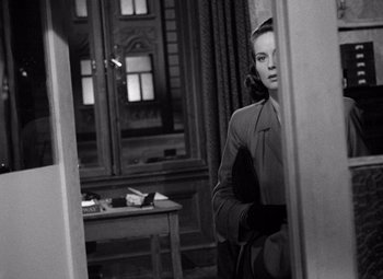 Movie still from “The Third Man” (1949), directed by Carol Reed – A black and white photo of a woman standing in front of a mirror; Medium shot, Over the shoulder angle