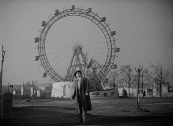 Movie still from “The Third Man” (1949), directed by Carol Reed – A man standing in front of a ferris wheel in an amusement park; Wide shot, Low angle