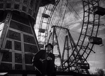 Movie still from “The Third Man” (1949), directed by Carol Reed – A man standing in front of a ferris wheel; Wide shot, Low angle