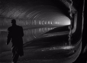 Movie still from “The Third Man” (1949), directed by Carol Reed – A man standing in front of a water fall; Wide shot, High angle