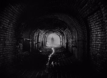 Movie still from “The Third Man” (1949), directed by Carol Reed – A person is walking through a dark tunnel; Extreme Wide shot, Low angle
