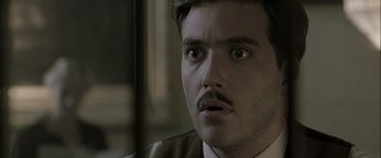 Movie still from “The Thirteenth Floor” (1999), directed by Josef Rusnak – A person wearing a suit and mustache; Close Up shot, Low angle