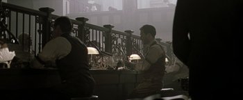 Movie still from “The Thirteenth Floor” (1999), directed by Josef Rusnak – A man sitting at a table in front of some lights; Wide shot, High angle