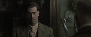 Movie still from “The Thirteenth Floor” (1999), directed by Josef Rusnak – A man in a suit and tie standing in front of a mirror; Close Up shot, Low angle