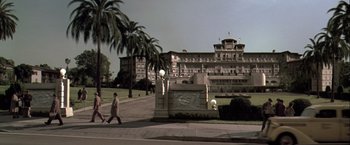 Movie still from “The Thirteenth Floor” (1999), directed by Josef Rusnak – A man walking down the street in front of a large building; Extreme Wide shot, Low angle