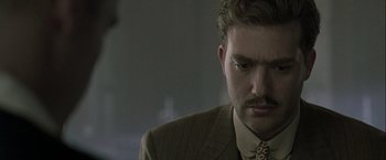 Movie still from “The Thirteenth Floor” (1999), directed by Josef Rusnak – A person wearing a suit and tie; Close Up shot, Over the shoulder angle