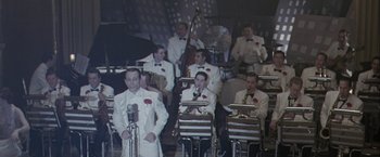 Movie still from “The Thirteenth Floor” (1999), directed by Josef Rusnak – A group of men in white suits are playing a band; Wide shot, High angle