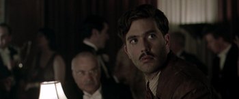 Movie still from “The Thirteenth Floor” (1999), directed by Josef Rusnak – A man in a suit and tie looking at the camera with another man behind him; Close Up shot, Over the shoulder angle