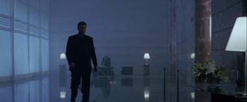 Movie still from “The Thirteenth Floor” (1999), directed by Josef Rusnak – A man in a black suit is holding a mop in a dark room; Wide shot, Low angle