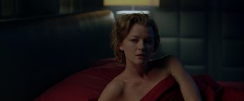 Movie still from “The Thirteenth Floor” (1999), directed by Josef Rusnak – A woman sitting on top of a couch in a room; Close Up shot, Low angle