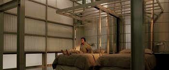 Movie still from “The Thirteenth Floor” (1999), directed by Josef Rusnak – A man sitting on top of a bed next to a window; Wide shot, High angle