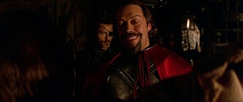 Movie still from “The Three Musketeers” (1993), directed by Stephen Herek – A man with a beard and a red cape; Close Up shot, Over the shoulder angle