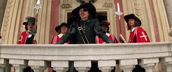 Movie still from “The Three Musketeers” (1993), directed by Stephen Herek – A group of men standing next to each other on top of a building; Medium shot, Low angle