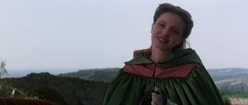 Movie still from “The Three Musketeers” (1993), directed by Stephen Herek – A woman in a green and red dress smiling for the camera; Close Up shot, Low angle