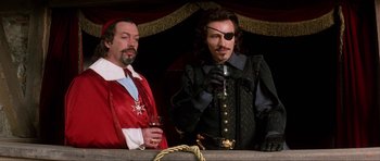 Movie still from “The Three Musketeers” (1993), directed by Stephen Herek – Two men dressed in medieval clothing , one holding a glass of wine and the other holding a bottle of wine; Medium shot, Low angle
