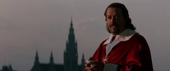 Movie still from “The Three Musketeers” (1993), directed by Stephen Herek – A man dressed in a red robe holding a spray bottle; Close Up shot, Low angle