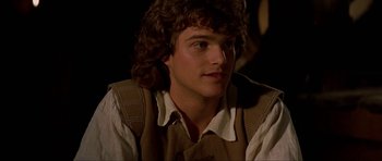 Movie still from “The Three Musketeers” (1993), directed by Stephen Herek – A man with long curly hair wearing a shirt and vest; Close Up shot, Over the shoulder angle