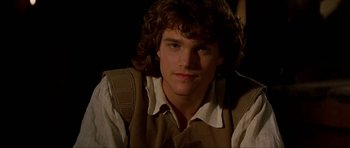 Movie still from “The Three Musketeers” (1993), directed by Stephen Herek – A man with long curly hair wearing a shirt and vest; Close Up shot, High angle