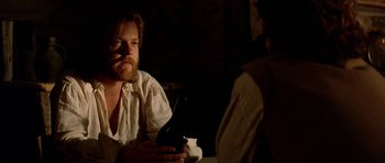 Movie still from “The Three Musketeers” (1993), directed by Stephen Herek – A man sitting in front of another man holding a cell phone; Close Up shot, Over the shoulder angle