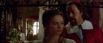 Movie still from “The Three Musketeers” (1993), directed by Stephen Herek – A man and a woman standing next to each other in a room; Close Up shot, Over the shoulder angle