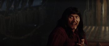 Movie still from “The Three Musketeers” (1993), directed by Stephen Herek – A man with long black hair is smiling for the camera; Close Up shot, Over the shoulder angle
