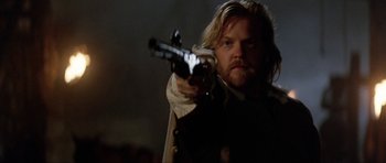 Movie still from “The Three Musketeers” (1993), directed by Stephen Herek – A man holding a gun in a dark room; Close Up shot, Over the shoulder angle