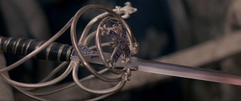 Movie still from “The Three Musketeers” (1993), directed by Stephen Herek – View of a sword with a blue cross on it; Extreme Close Up shot, High angle