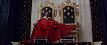 Movie still from “The Three Musketeers” (1993), directed by Stephen Herek – A man sitting on a throne in a room; Wide shot, Low angle