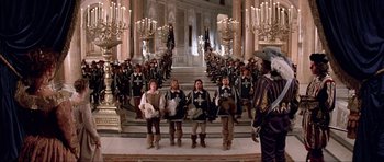 Movie still from “The Three Musketeers” (1993), directed by Stephen Herek – A group of men in medieval garb standing in front of a crowd of candles; Wide shot, High angle