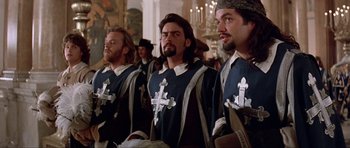Movie still from “The Three Musketeers” (1993), directed by Stephen Herek – A group of men standing next to each other in medieval garb; Medium shot, Low angle