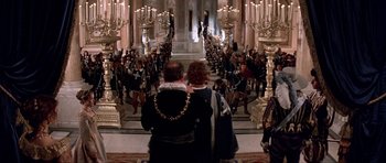 Movie still from “The Three Musketeers” (1993), directed by Stephen Herek – Two people are standing in front of a crowd of people; Wide shot, High angle