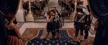 Movie still from “The Three Musketeers” (1993), directed by Stephen Herek – A couple of people that are kissing in a room; Wide shot, High angle
