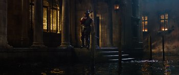 Movie still from “The Three Musketeers” (2011), directed by Paul W.S. Anderson – A man dressed as a medieval knight jumping over water; Wide shot, Low angle