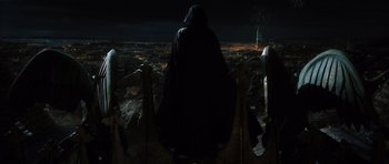Movie still from “The Three Musketeers” (2011), directed by Paul W.S. Anderson – A person in a hooded cloak standing on a balcony; Wide shot, Low angle