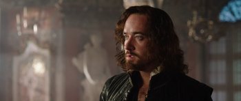Movie still from “The Three Musketeers” (2011), directed by Paul W.S. Anderson – A person with long hair and a beard; Close Up shot, Over the shoulder angle