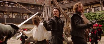 Movie still from “The Three Musketeers” (2011), directed by Paul W.S. Anderson – A man holding a sword in front of another man; Medium shot, Low angle