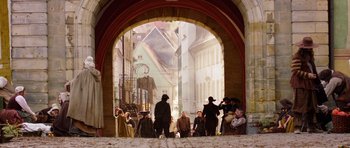 Movie still from “The Three Musketeers” (2011), directed by Paul W.S. Anderson – A group of people standing under an archway; Wide shot, Over the shoulder angle