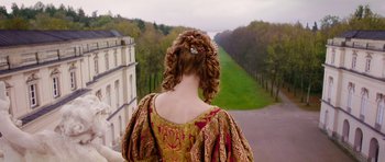 Movie still from “The Three Musketeers” (2011), directed by Paul W.S. Anderson – A woman in an old fashioned dress looking out over a park; Medium shot, Low angle