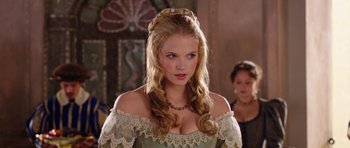 Movie still from “The Three Musketeers” (2011), directed by Paul W.S. Anderson – A woman with long blonde hair wearing a green dress; Close Up shot, Over the shoulder angle