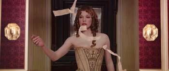 Movie still from “The Three Musketeers” (2011), directed by Paul W.S. Anderson – A beautiful woman in a dress with papers flying around her; Medium shot, Low angle