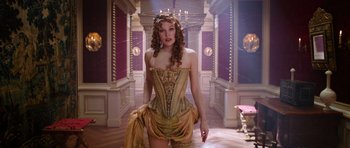 Movie still from “The Three Musketeers” (2011), directed by Paul W.S. Anderson – A beautiful woman in a yellow dress and a crown in a room; Medium shot, Low angle