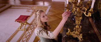Movie still from “The Three Musketeers” (2011), directed by Paul W.S. Anderson – A beautiful young lady holding a candle in a room; Medium shot, Over the shoulder angle